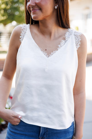 
Portrait view of the white satin eyelash lace camisole top highlighting the fine eyelash fringe lace detail framed along the V-neck cutout. Shows the soft lustrous shine of the fabric and the thick lace shoulder strap trim.