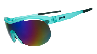 Angled side view of the Goodr Cue the Slow-Mo Montage sunglasses against a transparent background. This perspective highlights the aerodynamic wrap-around shield lens and the translucent teal temple arm, which features the classic "goodr" logo embedded in dark blue text. The view also reveals contrasting dark grip detailing along the tips of the temple arms designed for a secure, bounce-free fit.