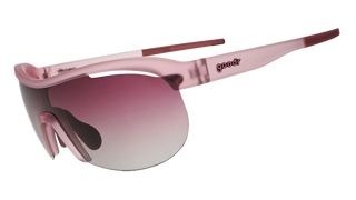Angled side view of the Goodr Human Energy Drink sunglasses against a transparent background. This perspective highlights the aerodynamic wrap-around shield lens and the translucent light pink temple arm, which features the classic "goodr" logo embedded in dark pink text. The view also reveals contrasting deep pink rubber grip detailing along the inner tips of the temple arms and the nose pad, designed for a secure, bounce-free fit.