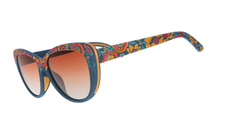 Angled side view of the Goodr Prairie Mystique sunglasses against a transparent background. This perspective highlights the continuous dark teal-blue floral pattern extending down the temple arms, which features the classic "goodr" logo embedded in orange text. The view also reveals a contrasting bright orange inner frame edge and showcases the curve of the amber gradient lenses.