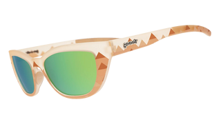 Angled side view of the Goodr Pyramid Scheming in Cairo sunglasses against a transparent background. This perspective highlights the continuous translucent pale beige frame and the geometric, earth-toned triangle pattern extending down the temple arms. The classic "goodr" logo is prominently embedded in metallic text on the side, while textured translucent nose pads and the curved reflective yellow-green lenses emphasize the blend of stylish design and athletic grip.