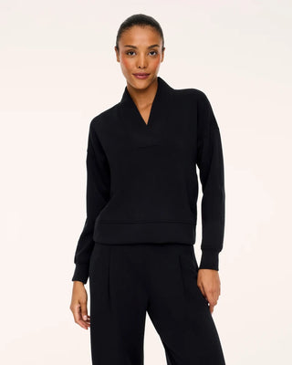 Model wearing the Very Black AirEssentials V-neck pullover paired with matching black pleated wide-leg trousers. This relaxed-fit athleisure top features an architectural split shawl collar that creates a flattering deep V-neckline, subtle drop-shoulder seams, fitted ribbed cuffs, and a wide banded hem against a crisp, neutral studio backdrop
