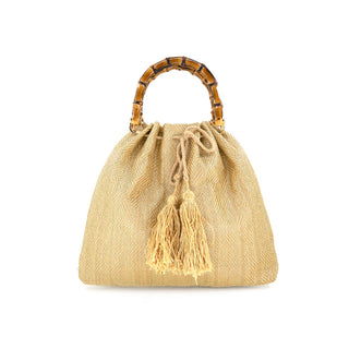 A chic, gold-toned woven straw pouch handbag featuring a structured, dark-stained bamboo top handle with natural wood grain and knots. The bag showcases an elegant herringbone textured weave and a drawstring closure finished with two oversized, tiered raffia tassels in a matching champagne gold hue. Designed with a flat base and a voluminous, relaxed silhouette for a sophisticated "boho-luxury" aesthetic.