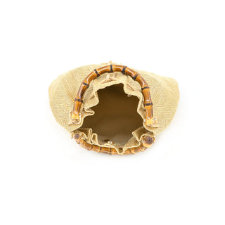 An overhead, birds-eye view looking into the open interior of the gold woven straw pouch. The image highlights a spacious, fully lined inner compartment in a neutral tan fabric, featuring a small zippered security pocket and a magnetic snap closure for added functionality. The dark-stained, burnt bamboo handles are shown in detail, attached to the metallic-flecked herringbone straw body with gold-toned hardware, illustrating the bag’s wide-opening "bucket" silhouette and premium craftsmanship.