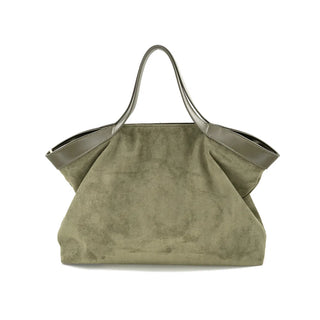 Front view of a spacious olive green suede tote bag set against a crisp white background. The handbag features a relaxed, oversized flared silhouette with softly draped sides and a wide top opening. The textured suede body is elegantly contrasted by smooth, tonal leather-look trim along the top edge, which seamlessly extends into two slender, structured shoulder straps for a chic and comfortable carry.