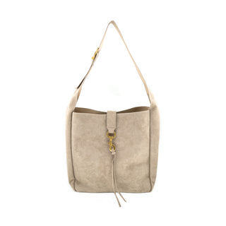 Product shot of a structured, soft taupe beige suede shoulder tote bag against a plain white background. Highlights the velvety faux-suede texture, a center strap closure secured by a gold swivel snap hook with dangling fringe tassels, and an adjustable flat shoulder strap with a gold-tone buckle.