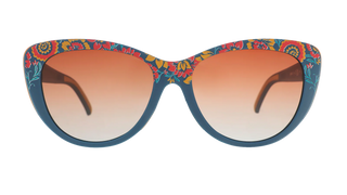 Front view of the Goodr Prairie Mystique sunglasses against a transparent background. The eyewear features a bold, dark teal-blue, softly rounded cat-eye frame decorated with a vibrant, vintage-inspired botanical pattern in shades of red, yellow, and orange. The lenses offer a warm, amber-to-clear gradient tint.