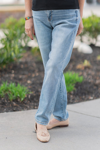 A close-up front view of the Judy Blue Echo Wash Denim, highlighting the authentic vintage wash and premium performance stretch fabric. The detail showcases the slim-fit cut that hugs the legs, paired with nude leather tassel loafers. The image emphasizes the figure-flattering mid-rise waistband and clean tonal stitching.