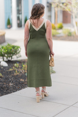 A full-length back view of the Annalise Colorblock Midi Dress emphasizing the continuous, sleek column silhouette and the high-recovery ribbed texture. The back features a deep V-cut neckline mirrored by contrast cream banding, providing a sophisticated and structured frame for the shoulders. Paired with cream platform heels, this angle demonstrates the dress's statuesque drape and its ability to maintain a polished look from every direction.