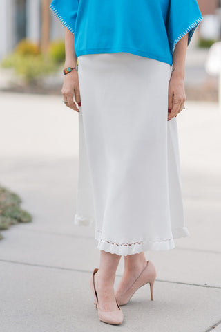 A detailed front view highlighting the artisanal hem of the Willow Whisper Midi Skirt. This shot showcases the intricate eyelet lattice insert and the dainty scalloped ruffle edge that provides a vintage-inspired romance. The premium, mid-weight woven fabric is visible, offering a smooth, silken finish and total opacity for a polished, high-end boutique feel.