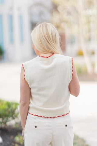 The back view of the Cape Cod Catch Knit emphasizing its clean, structured silhouette and high-end construction. The solid cream knit back is framed by the decorative red whipstitching at the neck, shoulders, and ribbed hemline. Paired with cream trousers, this angle demonstrates the vest's tailored yet relaxed fit and its ability to sit perfectly at the waistband for a flattering, bulk-free look.