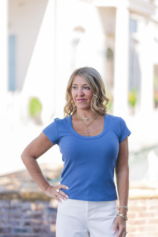 A portrait view highlighting the flattering scoop neckline and standard clean-cut shoulders of the navy Z Supply Leisurely Tee. The image captures the ultra-luxurious texture of the heavy soft-washed slub rib blend, cleanly skimming the model's natural figure without clinging. The look is elevated with a bold gold chain Y-necklace, showcasing the tee's versatility as a polished foundation piece.