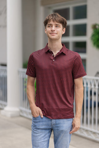 A mid-shot view highlighting the tailored fit of the Georgia Performance Polo on a male model. The graphic print features an intricate micro-pattern of red state outlines accented with tiny stars set against a deep maroon base. The shirt is designed with a structured polo collar and a clean three-button front placket with matching maroon buttons, left slightly unbuttoned to reveal a gold chain necklace. The model has one hand tucked into his pocket, showing off the lightweight polyester-spandex blend materi