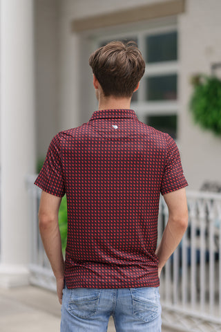 A full-length back view of the Georgia Performance Polo, emphasizing its clean silhouette and premium performance fit. The continuous micro-print of red state silhouettes creates a textured visual effect across the shoulders, back panel, and short sleeves. A small, white minimalist brand logo is positioned centrally just beneath the rear collar seam. The straight bottom hem sits neatly over light-wash blue jeans as the model stands looking ahead.