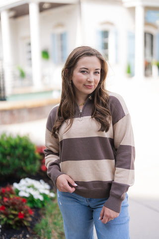 A portrait view of the Iced Mocha Bold Stripe Knit highlighting the fine-gauge knit texture and metal half-zip neckline. The shot details the open ribbed collar, low-slung shoulder seams, and wide mocha brown and beige block stripes, styled effortlessly with light-wash denim and a subtle gold chain necklace.