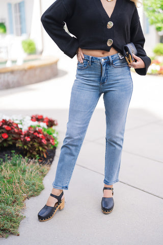 A detailed waist-to-hem close-up shot highlighting the front fit of the high-rise Judy Blue Peggy Ankle Straight Jeans. The view showcases the tummy control waistband construction, traditional five-pocket design, light whiskering across the hips, and the clean 28-inch straight leg hemline falling just above black leather wooden clogs.