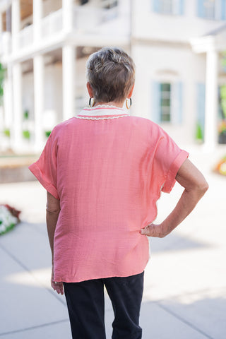 Back view of the Sweet Peach Puff-Sleeve Top displaying the smooth back panel cut in a boxy, airy silhouette. Details the continuation of the cream lace trim extending around the back of the collar, wide cuffed sleeves, and a loose straight hemline worn untucked over black denim jeans.