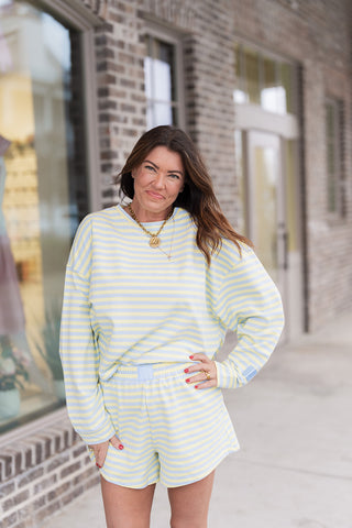 A portrait view of the Seaside Sorbet Sweatshirt highlighting the relaxed crew neckline and dropped shoulder seams. The image showcases the vibrant pastel stripes and slightly cropped length, paired with a gold coin necklace for an elevated off-duty look.