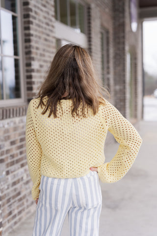 The back view of the Lemon Sherbert Top, showcasing the consistent open-knit construction and the relaxed, breathable fit of the sleeves. The knit's perforated texture is visible against the striped trousers, highlighting its lightweight comfort.