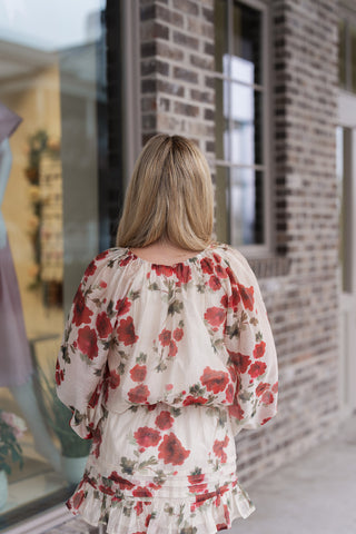The back of the Rosette Reverie Blouse showcasing the elegant gathered neckline and the discreet button closure at the nape of the neck. The sheer floral chiffon drapes softly, emphasizing the relaxed blouson silhouette and the consistent oversized botanical print throughout the design.