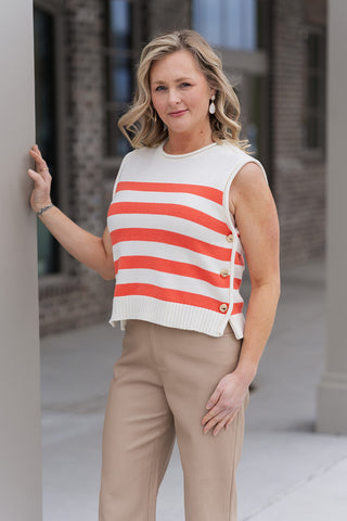 A close-up side profile of the Côte d'Azur Knit Top in Orange, focusing on the metallic glint of the gold-tone buttons and the reinforced ribbed crew neckline. The image showcases the quality of the textured knit construction and how the top sits perfectly at the natural hip.