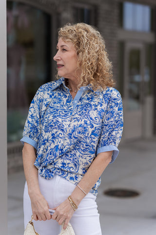 A detailed view of the Mediterranean Muse Blouse highlighting the clever use of contrast with a blue-and-white pinstripe pattern on the wide-banded cuffs and interior collar. The image emphasizes the high-quality woven fabric and the feminine volume of the structured half-length puff sleeves.