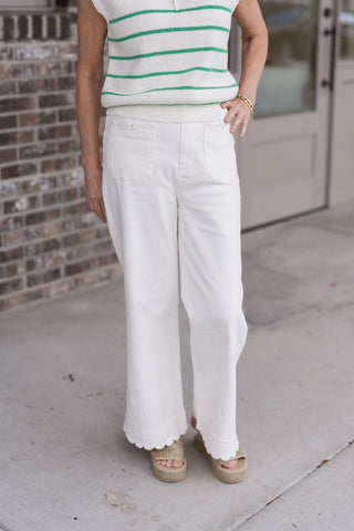 A detailed front view of the Scalloped Shoreline Wide-Leg Pants highlighting the exquisite scalloped trim detailing on the entry of the large front patch pockets. The image showcases the premium lightweight woven fabric and the secure zip fly and button closure, illustrating the pants' structured yet flowy boutique finish.