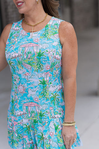 A detailed portrait view of the Cabana Club Pleat Dress highlighting the whimsical coastal print and the reinforced scoop neckline. The high-quality performance fabric is shown with tailored side seaming designed to contour the torso, emphasizing the intricate details of the sun and turtle motifs against the turquoise canvas.