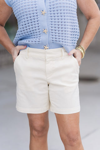 A close-up front view of the Dear John South Hampton Shorts in Ivory, highlighting the traditional zip-fly with button closure and functional belt loops. The premium fabric blend of cotton and spandex provides a tailored appearance with a touch of flexible stretch.