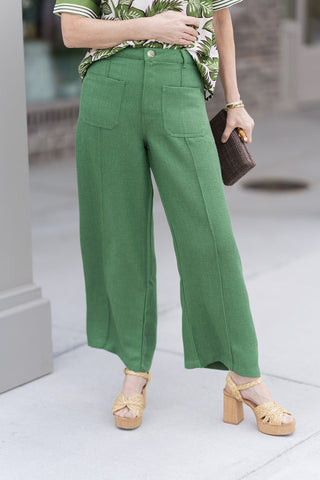 A detailed front view of the Clubhouse Classic Pants highlighting the spacious, top-entry front patch pockets and the traditional hardware, including a secure zip fly and button closure. The premium woven fabric is shown in a solid fern green, illustrating the tailored fit and functional belt loops designed for personalized boutique styling.