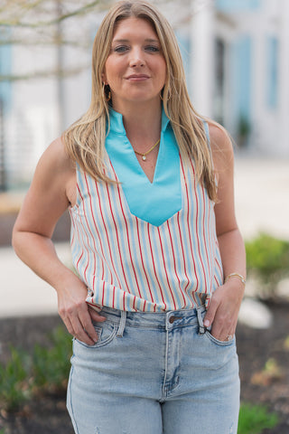 A portrait-style close-up highlighting the "preppy-chic" details of the Seaside Sorbet Tank. The image showcases the vibrant turquoise contrast collar and the slimming effect of the multi-color vertical striped pattern. The model is accessorized with a delicate gold pendant necklace and gold hoop earrings, emphasizing the top's face-framing neckline and breathable, non-sheer knit fabric.