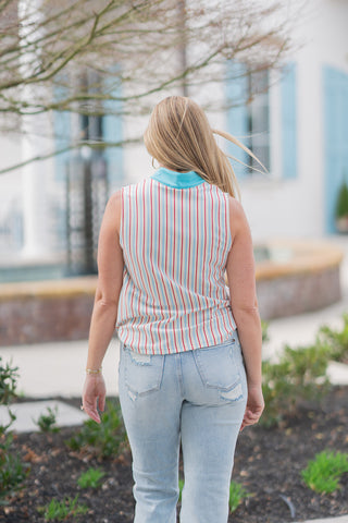 A full-length back view of the Seaside Sorbet Tank emphasizing its relaxed, flowy silhouette and featherlight feel. The vertical coral and blue stripes continue across the back, meeting the structured turquoise collar at the neckline. This angle highlights the top’s easy movement and polished drape when paired with relaxed-fit light-wash denim.