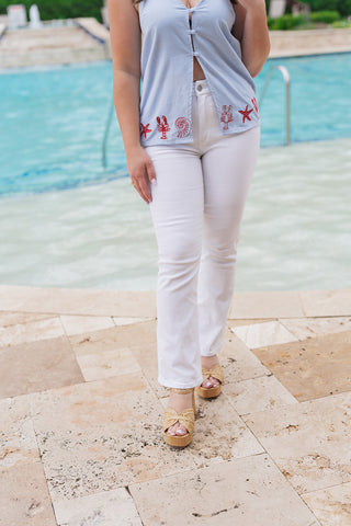 A detailed shot of the lower half of the Dear John Jeanne White Jeans, focusing on the slim fit through the thigh and the trendy cropped flare at the ankle. The "kick flare" silhouette is shown paired with braided jute platform heels, illustrating the perfect length for showcasing statement summer footwear against the backdrop of a luxury pool.