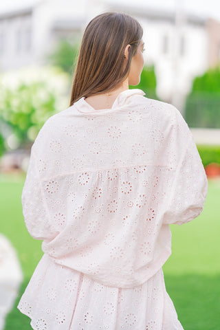 Rear view of a model from the waist up wearing the light pink Rosewater Romance Lace Blouse. The shot showcases the continuous allover floral eyelet cutouts and the horizontal yoke seam across the back, which features subtle gathering that relaxes into the airy cotton bodice and loose bubble puff sleeves.