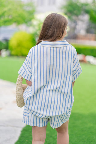 Rear view of a model from the thighs up showcasing the back construction of the Saint-Tropez Stripe Gauze Top. The image highlights the oversized, relaxed fit of the lightweight linen-look gauze fabric and the continuous vertical blue and white stripes across the shoulders and flowing back panel.