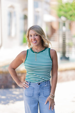 An upper body close-up of the Vineyard Resort Tank highlighting the modern high round crew neck and flattering rib-knit texture. The vibrant green and white horizontal sailor-inspired stripes are framed elegantly by solid forest green trim. Styled with layered gold chain necklaces, the sleeveless top contours gently to the silhouette for a polished, preppy flair.