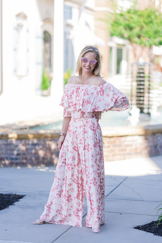 Full body front view of a smiling woman posing outdoors in the Bellini Brunch Set. This exquisite two-piece ensemble creates an elongated, coordinated illusion that resembles a high-end maxi dress while providing the modern comfort of trousers. The high-waisted wide-leg pants feature a clean, flat-front waistband that pairs seamlessly with the cropped, voluminous ruffled top. The look is elevated with pink cat-eye sunglasses and strappy nude block heels for the ultimate sun-drenched resort aesthetic.
