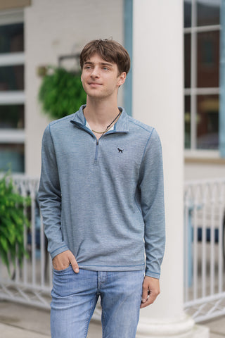 An upper-body portrait view of the Slate Harbor Zip Pullover showcasing its refined mock neck design. The tonal quarter-zip closure is styled unzipped halfway to reveal a white undershirt and a thin chain necklace. A small, subtle embroidered black dog logo is clearly visible on the left chest of the lightweight heathered fabric.