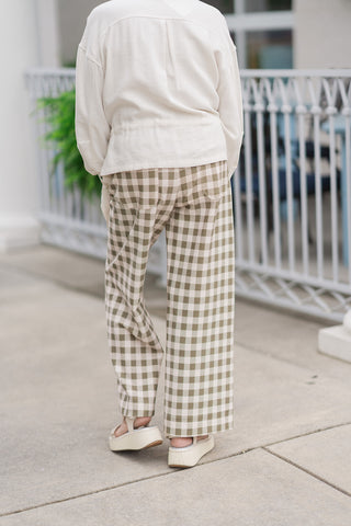 A back view from the waist down of the Olive Grove Wide-Leg Pants, showcasing the fit and pattern alignment of the relaxed wide-leg silhouette. The continuous olive-green and cream gingham check print runs seamlessly down the back of the legs to the cropped hemline, accented by traditional back patch pockets for a classic trouser finish.