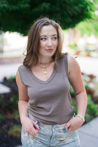 A portrait view of the Z Supply Ellie V-Neck Tank highlighting its clean, classic open V-neckline and supportive wide shoulder straps. The premium cotton baby rib knit fabric offers subtle textural depth, beautifully paired with a gold coin pendant necklace and floral-patterned denim jeans.