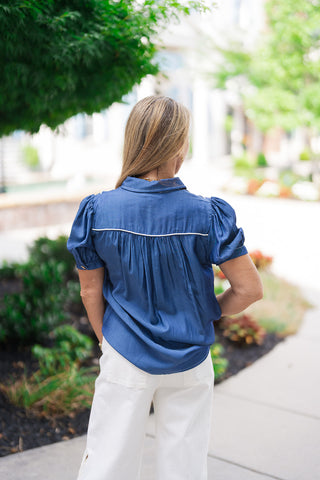 Back view of the Canyon Rosewood Embroidered Top highlighting the fluid, lightweight drape of the washed tencel fabric. This view emphasizes the classic western yoke construction across the shoulders, trimmed with a single line of cream rope piping and detailed with gentle gathers that create a relaxed, non-restrictive fit over the back of high-waisted white trousers.