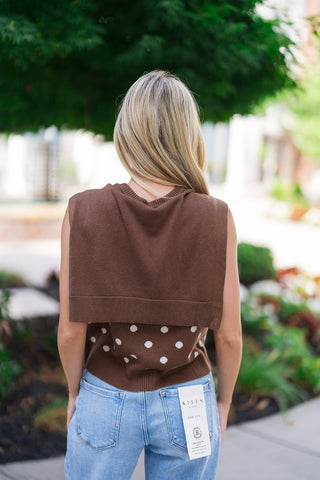Back view of the Nantucket Knit Dot Top showcasing the unique design layout of the attached solid knit accent. From behind, the built-in scarf element mimics a classic sweater cleanly draped over the shoulders and upper back, while the exposed lower portion reveals the continuous polka dot pattern and structured ribbed hemline resting against light-wash high-rise denim.