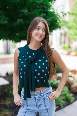 A medium close-up view highlighting the sophisticated country-club aesthetic of the Nantucket Knit Dot Top. The image showcases the soft, premium sweater knit texture and the seamless appearance of the attached solid knit scarf tie detail. The ribbed crew neckline and structured sleeveless cut frame the face beautifully, creating an effortless layered illusion without any added bulk.