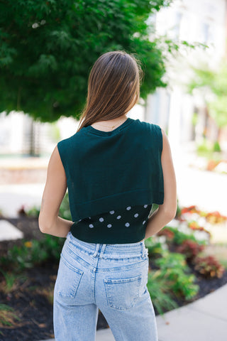 Back view of the Nantucket Knit Dot Top showcasing the unique design layout of the attached solid knit accent. From behind, the built-in scarf element mimics a classic sweater cleanly draped over the shoulders and upper back, while the exposed lower portion reveals the continuous polka dot pattern and structured ribbed hemline resting against light-wash high-rise denim.