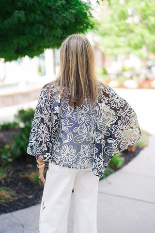 Back view of the Canyon Rosewood Embroidered Top highlighting the fluid, lightweight drape of the washed tencel fabric. This view emphasizes the classic western yoke construction across the shoulders, trimmed with a single line of cream rope piping and detailed with gentle gathers that create a relaxed, non-restrictive fit over the back of high-waisted white trousers.