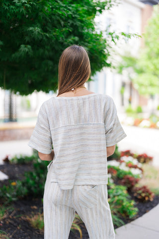 An upper body back view of the Ocean Breeze Lounge Set top, highlighting its relaxed, oversized boxy silhouette and clean horizontal stripe paneling. The textured, breathable knit blend fits loosely across the shoulders and drapes effortlessly down to a straight hemline, showing off an easy, laid-back resort aesthetic.