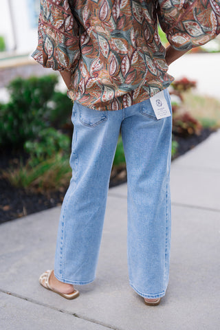 Back view focusing on the Risen Canyon Fade Cropped Denim to illustrate the high-end tailored fit from behind. The shot highlights two traditional, symmetrical back patch pockets cleanly integrated into the mid-weight stretch denim. The barrel silhouette curves gently before resting at a clean cropped hemline just above the ankles.