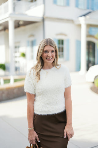 Close-up profile view highlighting the soft, feathered eyelash knit texture of the off-white short-sleeve sweater and its comfortable sleeve cuff finish.