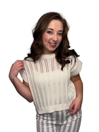 The Rosewater Ribbed Knit in Off-White featuring a structured cap sleeve and a breathable open-knit design. Shown on a model with white and gray vertical striped pants.