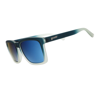 Angled side view of the Goodr Lost in the Labyrinth sunglasses against a white background. This perspective highlights the continuous matte gradient finish extending down the temple arms, shifting seamlessly from dark teal to translucent frosted clear at the tips. The classic "goodr" logo is embedded in light metallic text on the temple arm, while the reflective blue lenses complete the cool-toned aesthetic.